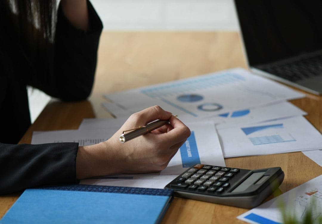 Scrivania con calcolatrice, prospetti e grafici durante la stesura di un piano economico